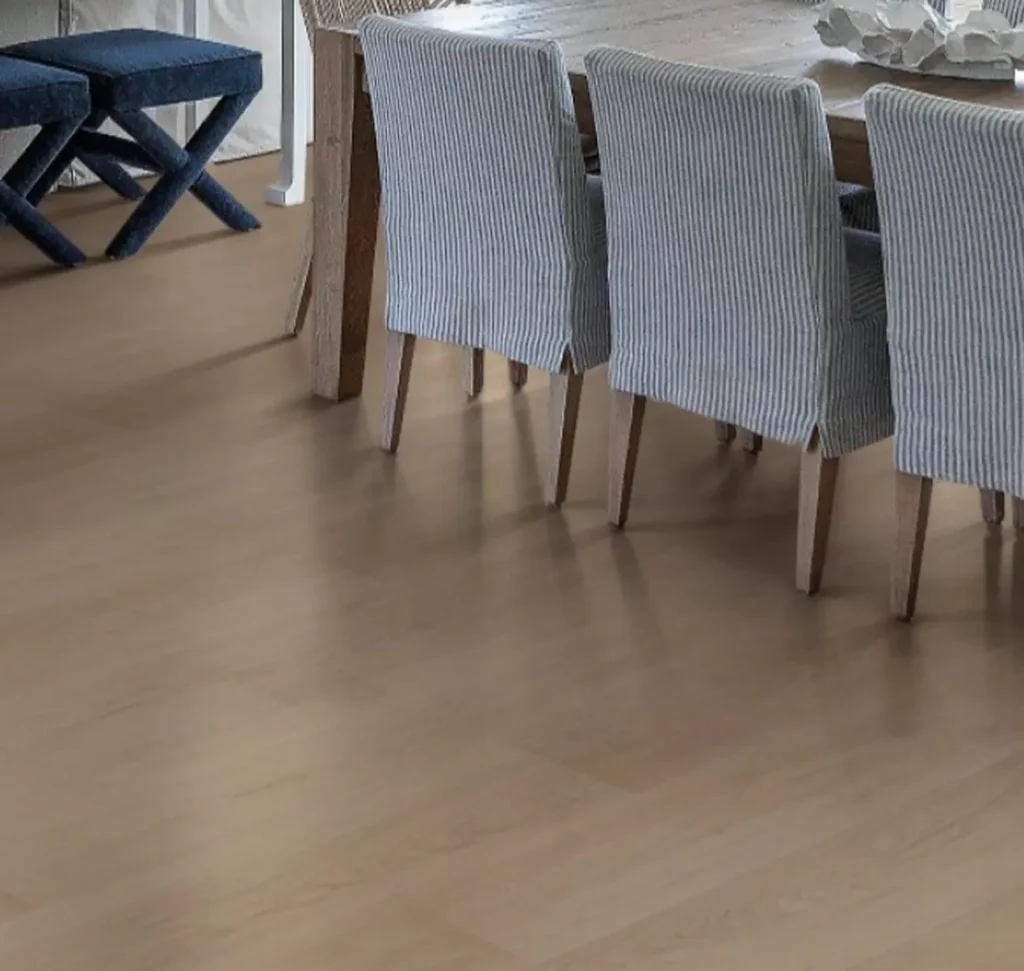 Modern dining room featuring light-toned smooth hardwood flooring, a wooden dining table, and chairs with blue and white striped fabric slipcovers.