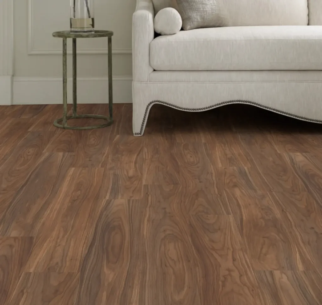 Rich walnut luxury vinyl flooring with prominent wood knots, paired with an elegant cream scalloped sofa and a slim brass side table.